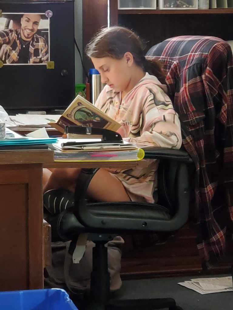 Student reading in Ms. Straw's chair.