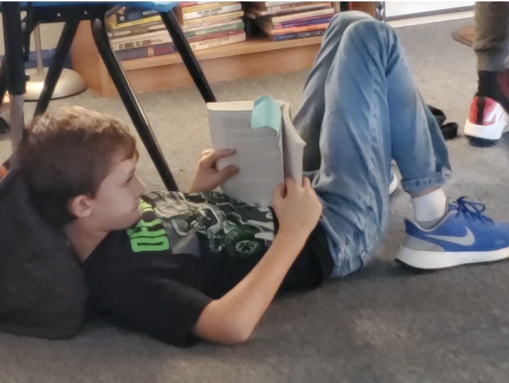 Student laying on their back reading a book.